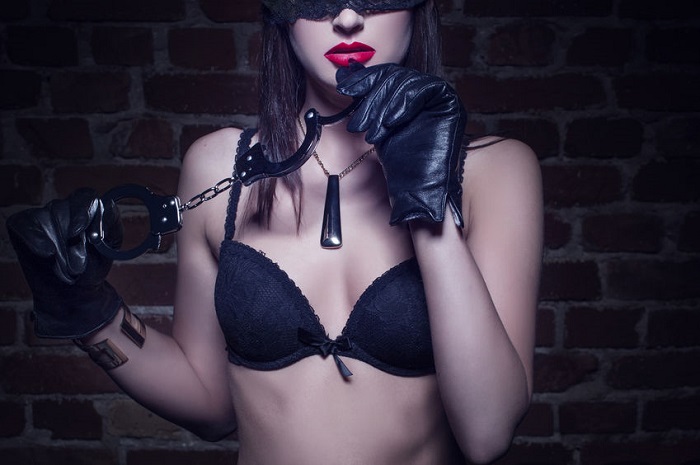 Sexy woman in lace eye cover holding handcuffs